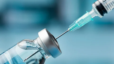 the image shows a syringe and a bottle of vaccine.