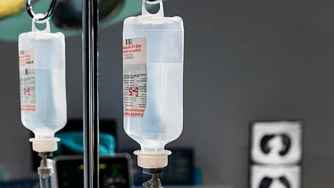 A hospital room featuring IV bags hanging and a medical monitor displaying patient information.