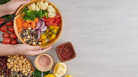 A variety of vegetarian food including vegetables, chickpeas, lentils and fruits arranged in salad bowls.