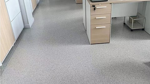 An image of a grey floor of an office with some furniture.
