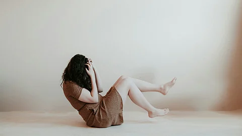 A woman sits with knees up, reflecting on chest pain not caused by a heart attack.