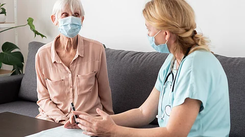 A healthcare professional having a discussion with an elderly woman.