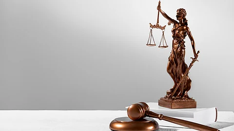 A bronze statue of a lady justice carrying a scale and a sword kept near a judge's gavel.