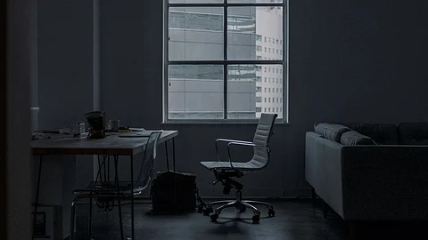 A dimly lit room featuring a couch and a desk, creating a cozy yet professional atmosphere.