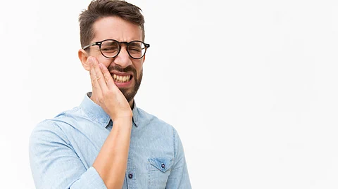 A man is holding his cheek in distress.