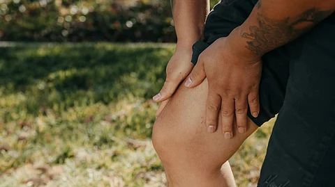 A man holding his knees outdoors.