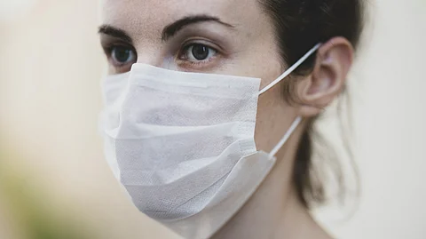 A girl with depressed expression wearing a white mask.