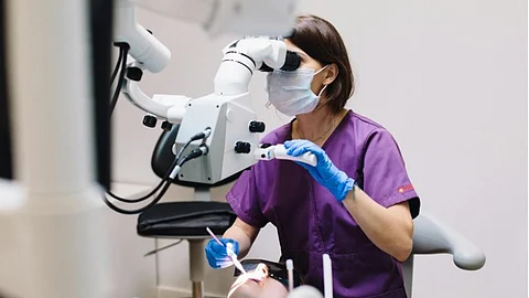 A dentist doing a procedure through a dental microscope.