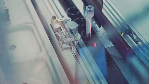Close-up of a high-tech medical device or laboratory machine analyzing a sample vial using automated precision equipment.