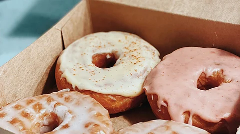 Image showing glazed donuts in a brown cardboard box.