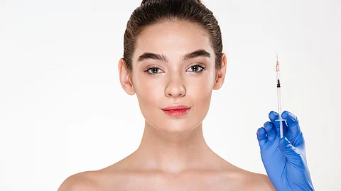 Image of a woman preparing to take botox injections from a doctor wearing gloves.