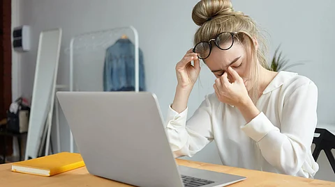 A woman rubbing her eyes off after prolonged sitting in front on laptop.