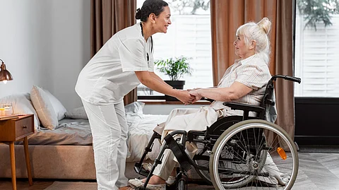 A female healthcare professional talking to an elderly woman in a wheelchair.