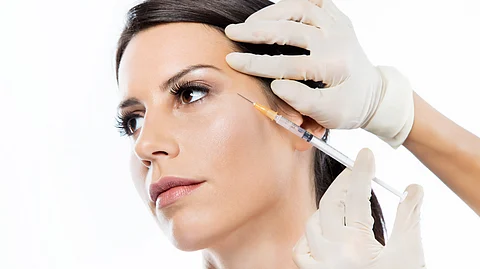 Young woman getting Botox done by a professional in a clinical setting.
