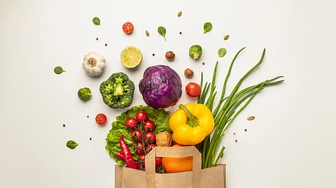 Top view of assorted vegetables falling out of the paper bag.