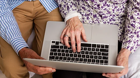 A top-down shot of a senior couple using a laptop.