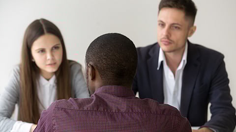 A young African American man is taking questions during an interview.