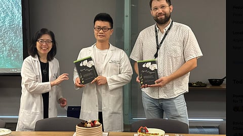 Image of a Chinese researcher standing with his colleague, being appreciated for completing his research.