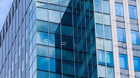 Image of a glass building having blue sky in background.