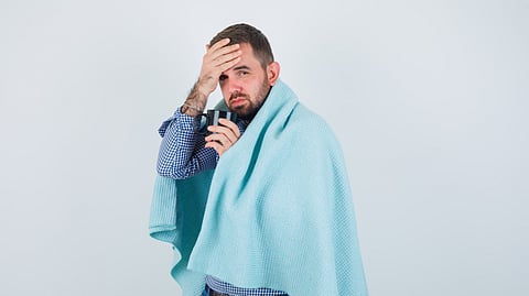 Image of a man suffering from illness carrying a blue towel and wearing a blue shirt.