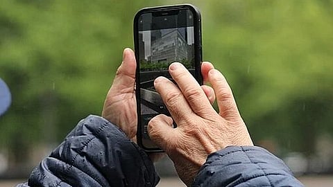 Image showing the hands of an old man using a cellphone to take an outdoor photo.