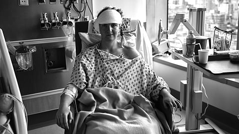 A black and white image of a Nicole Cutler sitting after an operation in the hospital room.