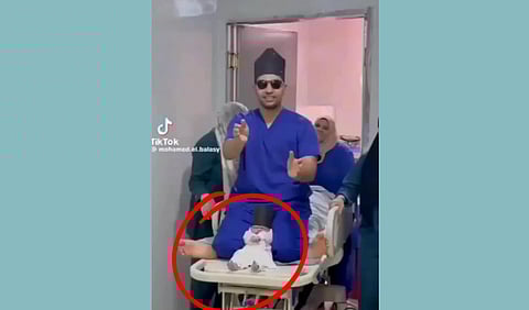 A doctor on his knees on a stretcher with a newborn between his legs.