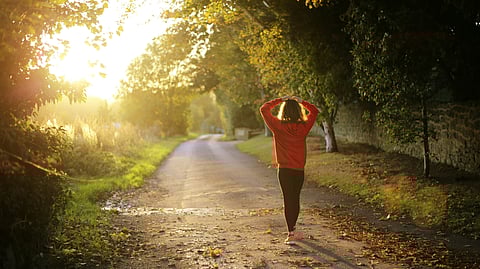 Image of a woman walking in the park alone in the morning.