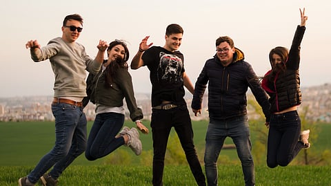 A group of people happily jumping over in the forest.