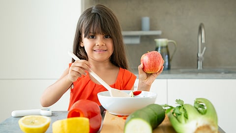 Image of a girl in good mood cooking a raw meal.