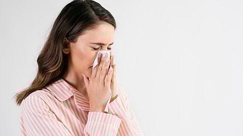 Image of a woman wearing pink striped shirt who might be suffering from flu.