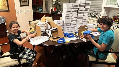 Image showing 2 kids packaging boxes in a dining room.