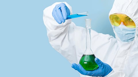 Image of a chemist pouring a chemical from test tube into a conical flask having another chemical.