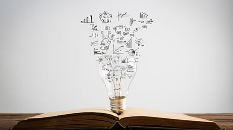 Image of research symbols coming out of the bulb on top of a book.