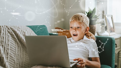 Image of a child wearing white t-shirt and have astonishing expressions by looking at the computer.