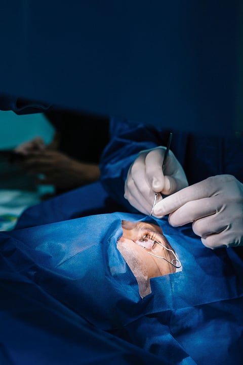 A person in blue scrubs is focused on performing a surgical operation in a sterile environment.