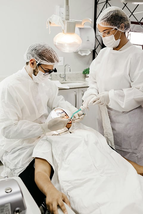 A man and woman in white coats attend to a patient in a medical setting, focused on providing care.