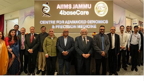 Group photo of officials and staff in front of AIIMS Jammu-4baseCare Centre for Advanced Genomics & Precision Medicine signboard.