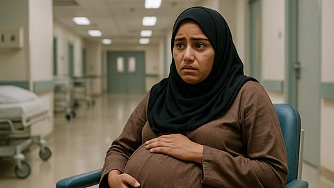 A fully pregnant woman sitting in a wheelchair alone in an hospital corridor.