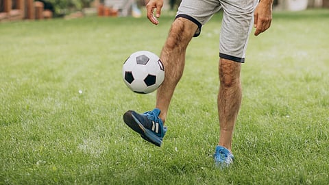 Image of an older person who is walking a football.