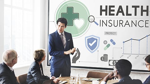 A man in blue suit is explaining some data to his colleagues about health insurance.