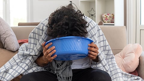 Image of a person vomiting in a blue bowl.