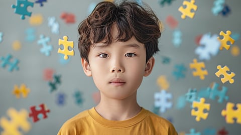 Image of a child wearing a yellow t-shirt and puzzle blocks.