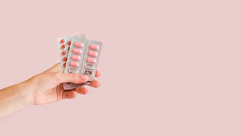Image of a person holding strips of pink tablets.