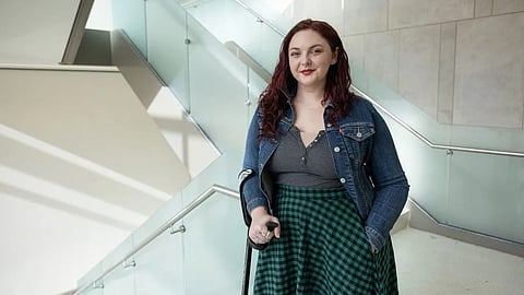 A woman with a cane stands on a stairway.