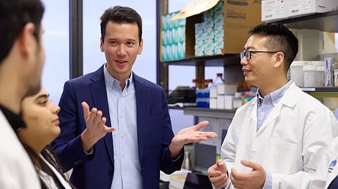 An image of a group of people in lab coats engaged in conversation.