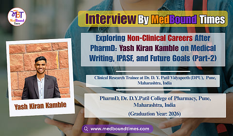 Smiling man in a black suit jacket and white shirt stands against a textured red brick wall. The image conveys a confident, cheerful tone.