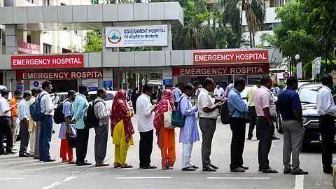 An image of people standing in long queue outside government hospital.