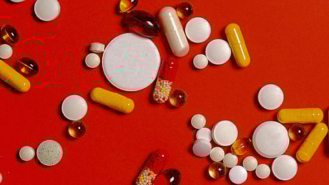 Image of capsules and tablets in front of a red colored background.