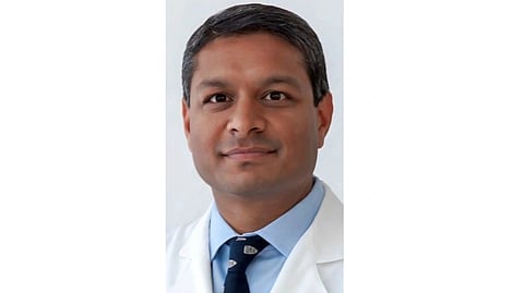 An image of professional man wearing a white coat, light blue shirt, and dark tie.